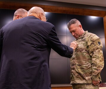 Fred Ressel, uncle of newly promoted Sgt. Maj. James Ressel, secures the new rank during the promotion ceremony July 7 at the Illinois Military Academy, Camp Lincoln, Springfield, Illinois.