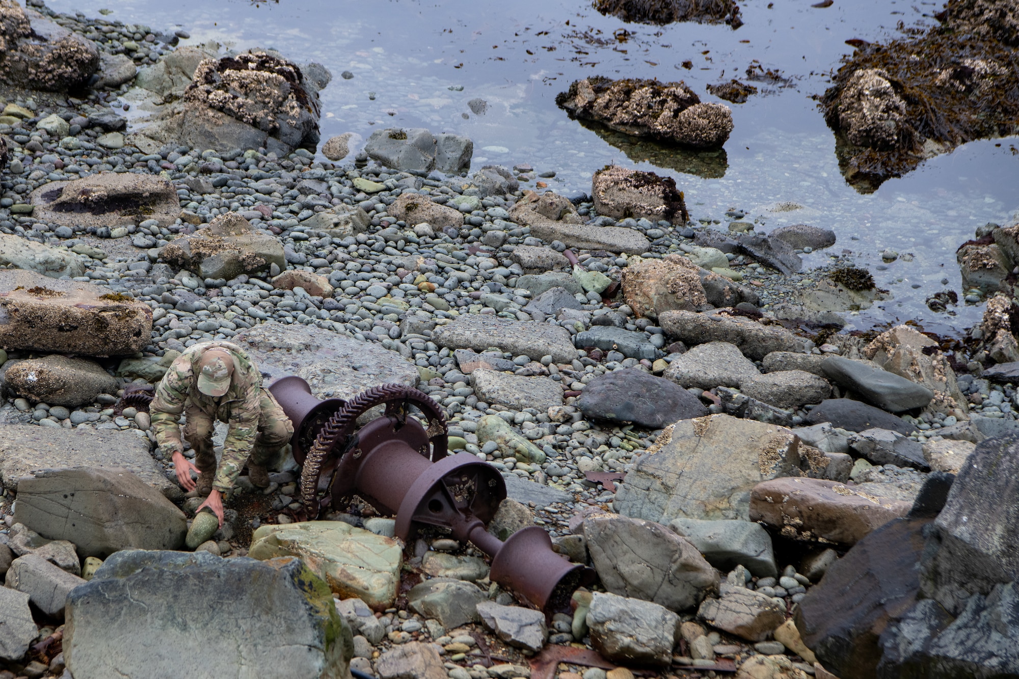 A photo of an EOD technician clearing debris from around a suspected UXO.