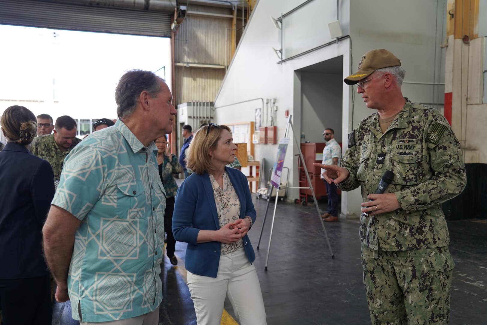 Rep. Ed Case, left, and Deputy Secretary of Defense Kathleen Hicks, center, receive a briefing from Pearl Harbor Naval Shipyard (PHNSY) Commander Capt. Richard Jones, right, during a tour of the shipyard.