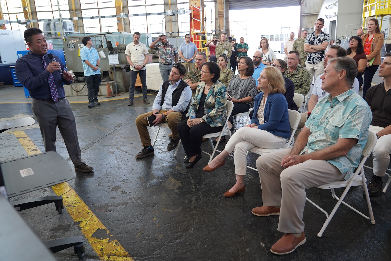 Deputy Secretary of Defense Kathleen Hicks, second from right, Assistant Secretary of Defense for Energy, Installations, and Environment, Brendan Owens, center, Sen. Mazie Hirono, right of center, and Rep. Ed Case, right, receive a briefing from Chad Nakamoto, Production Facilities and Plant Equipment Manager, left, during a tour of Pearl Harbor Naval Shipyard.