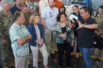 Deputy Secretary of Defense Kathleen Hicks, second from the left, Sen. Mazie Hirono, second from the right, Rep. Ed Case, left, receives a briefing during a tour of Pearl Harbor Naval Shipyard (PHNSY), Hawai’i, from John Morgan, Mechanical Superintendent for Code 930 (Shops 931/938).