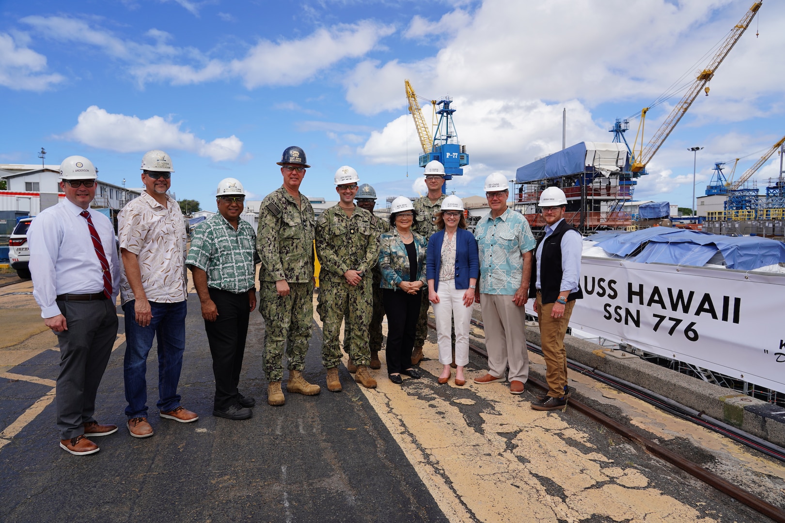 Deputy Secretary of Defense Kathleen Hicks, third from right, poses for a photo with shipyard leadership and state representatives, during a tour of Pearl Harbor Naval Shipyard