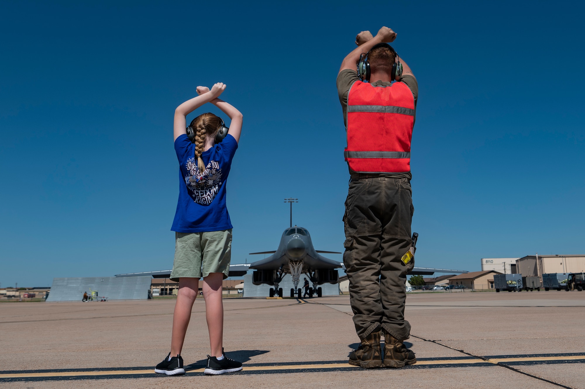 U.S. Air Force Staff Sgt. Zachary Gabriel, 337th Test and Evaluation Squadron crew chief, and Jennifer Kippie, daughter of Col. Kevin Kippie, 7th Bomb Wing vice commander, signals a B-1B Lancer to stop at Dyess Air Force Base, Texas, June 29, 2023. Kippie served at Dyess from June 11, 2021, to June 16, 2023. While at Dyess, Kippie was committed to excellence as he fostered financial innovation and proposals for the installation, created a Wing Welcome Center for new Airmen and worked in integrated teams to action the wing’s fiscal efforts. (U.S. Air Force photo by Senior Airman Ryan Hayman)