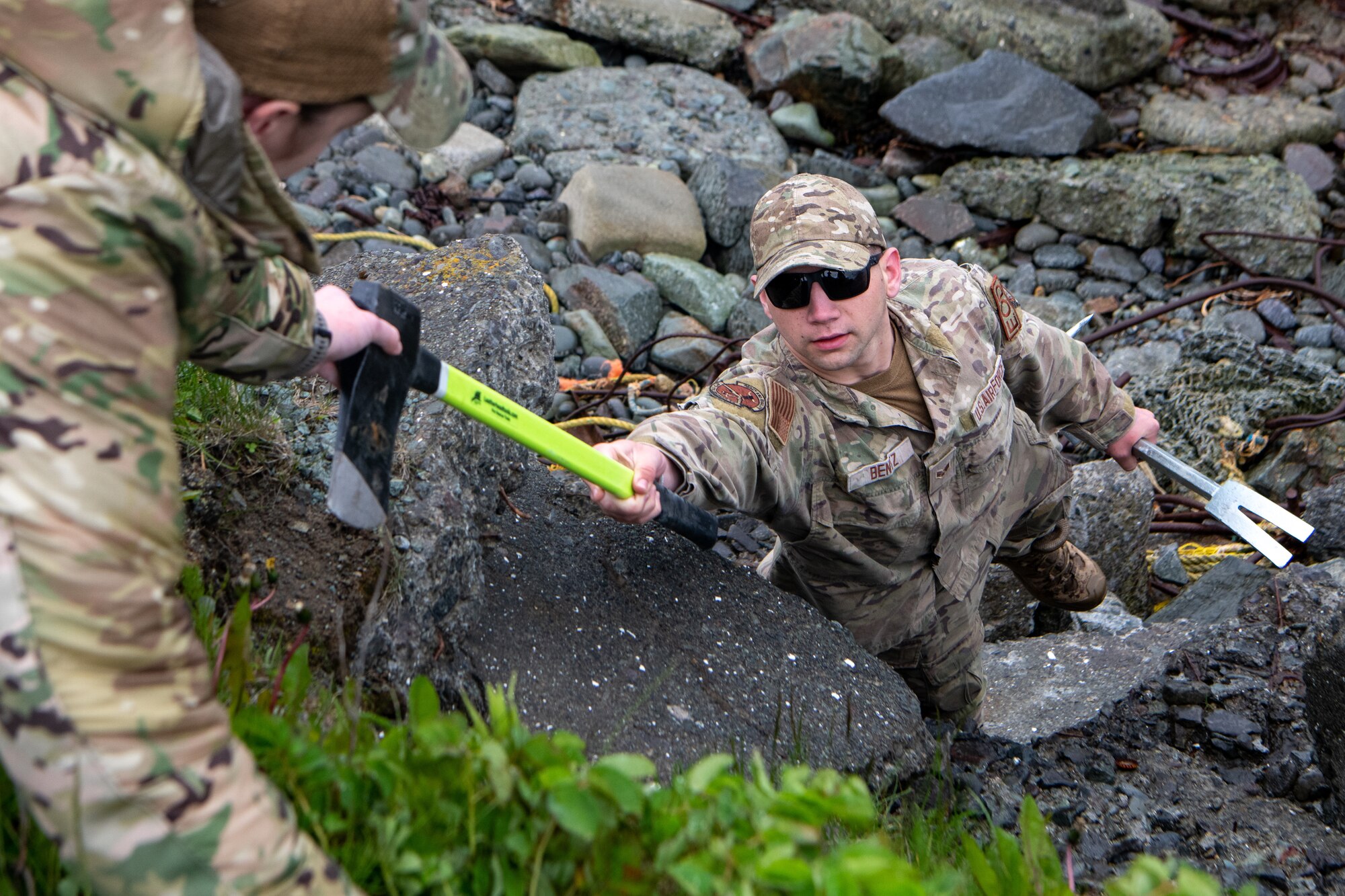 A photo of an EOD technician passing an ax up to another member of the Flight.