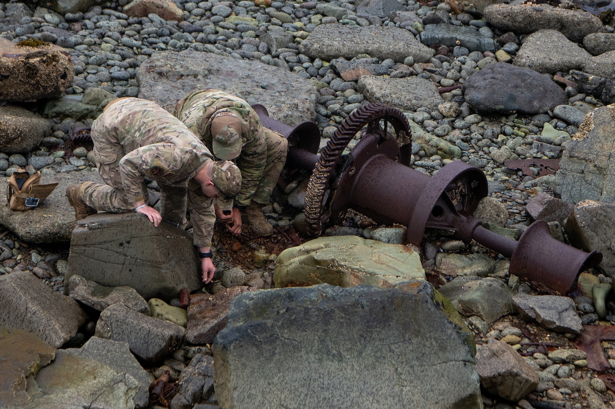 A photo of two EOD technicians clearing debris from arouind a suspected UXO.