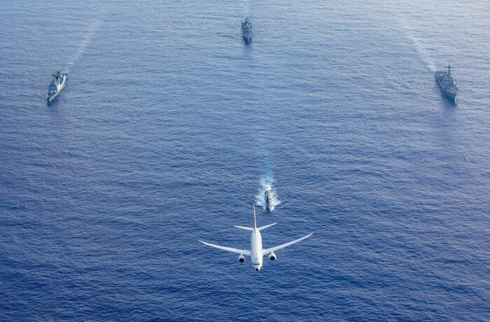 A U.S. Navy P-8 Poseidon flies above a formation of surface ships and submarines from the United States, Japan, and the Republic of Korea in the Philippine Sea during Pacific Vanguard 23