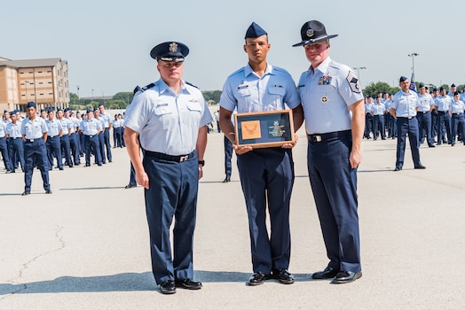  U.S. Space Force Specialist 3 Dakota Desrosiers, all-source intelligence analyst, center, receives the Top Graduate award during a Basic Military Training (BMT) coining ceremony at Joint Base San Antonio–Lackland, Texas, on June 21, 2023.
