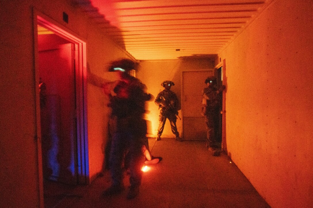 Marines stand in a hallway under an orange glow.