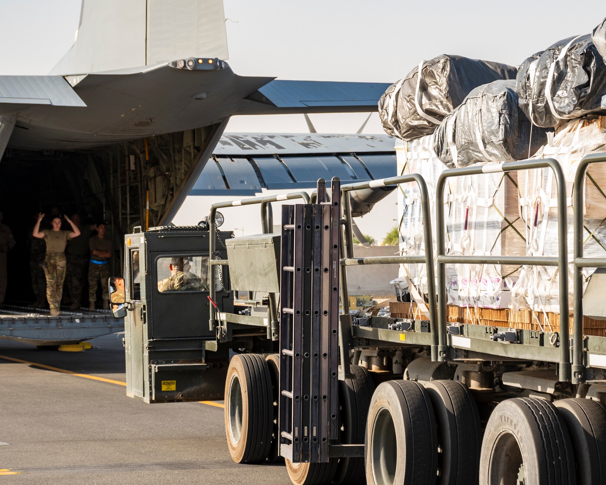 U.S. Air Force Airman 1st Class Tess Pouliot, 40th Expeditionary Airlift Squadron C-130 loadmaster, marshals a 60k cargo loader to an awaiting aircraft at Ali Al Salem Air Base, Kuwait, July 5, 2023.