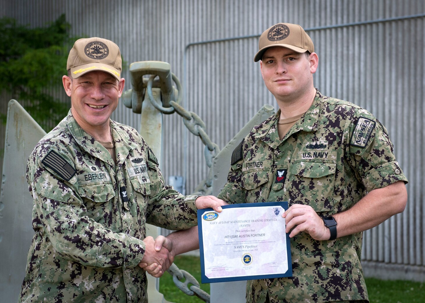 SILVERDALE, Wash. (Jun. 29, 2023) – U.S. Navy Capt. Michael D. Eberlein, left, commanding officer of Trident Refit Facility, Bangor (TRFB), presents a certificate to Hull Maintenance Technician 1st Class Austin Fortner. Fortner received recognition for completing his Navy Enlisted Classification (NEC) as a pipefitter under the Navy Afloat Maintenance Training Strategy (NAMTS) at TRFB. Fortner, currently attached to Naval Reserve Center-Houston, was mobilized under Surgemain from August 2020 to September 2021 where he enrolled under the NAMTS program to earn his pipefitter qualification. TRFB supports the nation’s strategic deterrence mission by repairing, incrementally overhauling, and modernizing Pacific Fleet strategic ballistic missile submarines during refits. (U.S. Navy photo by Mass Communication Specialist 2nd Class Sarah Christoph)