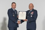 Two Air Force general officers in uniform shake hands while holding a letter of retirement