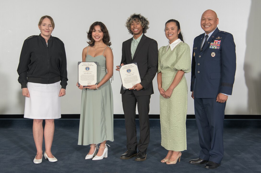 a group stand on a stage holding certificates