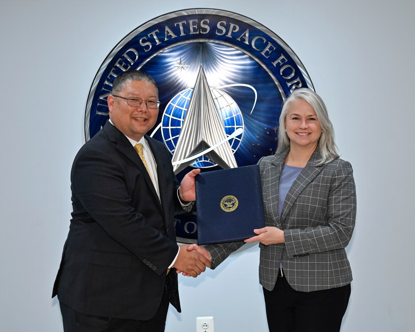 Wade Yamada, deputy director of staff for the Office of the Chief of Space Operations, and Lea Kirkwood, director of the Agile Combat Support Directorate for the Air Force Life Cycle Management Center, pose after signing a memorandum of agreement at the Pentagon, Arlington, Va., July 11, 2023. The agreement documented the partnership between the two organizations to develop, procure and provide ongoing support for new Space Force uniforms. (U.S. Air Force photo by Eric Dietrich)