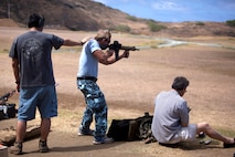 Neal Jensen, a former Marine corporal, provides support to U.S. Coast Guard Chief Petty Officer Michael Baxter as Baxter shoots during a recreational fire event at the Kaneohe Bay Range Training Facility, Aug. 9.