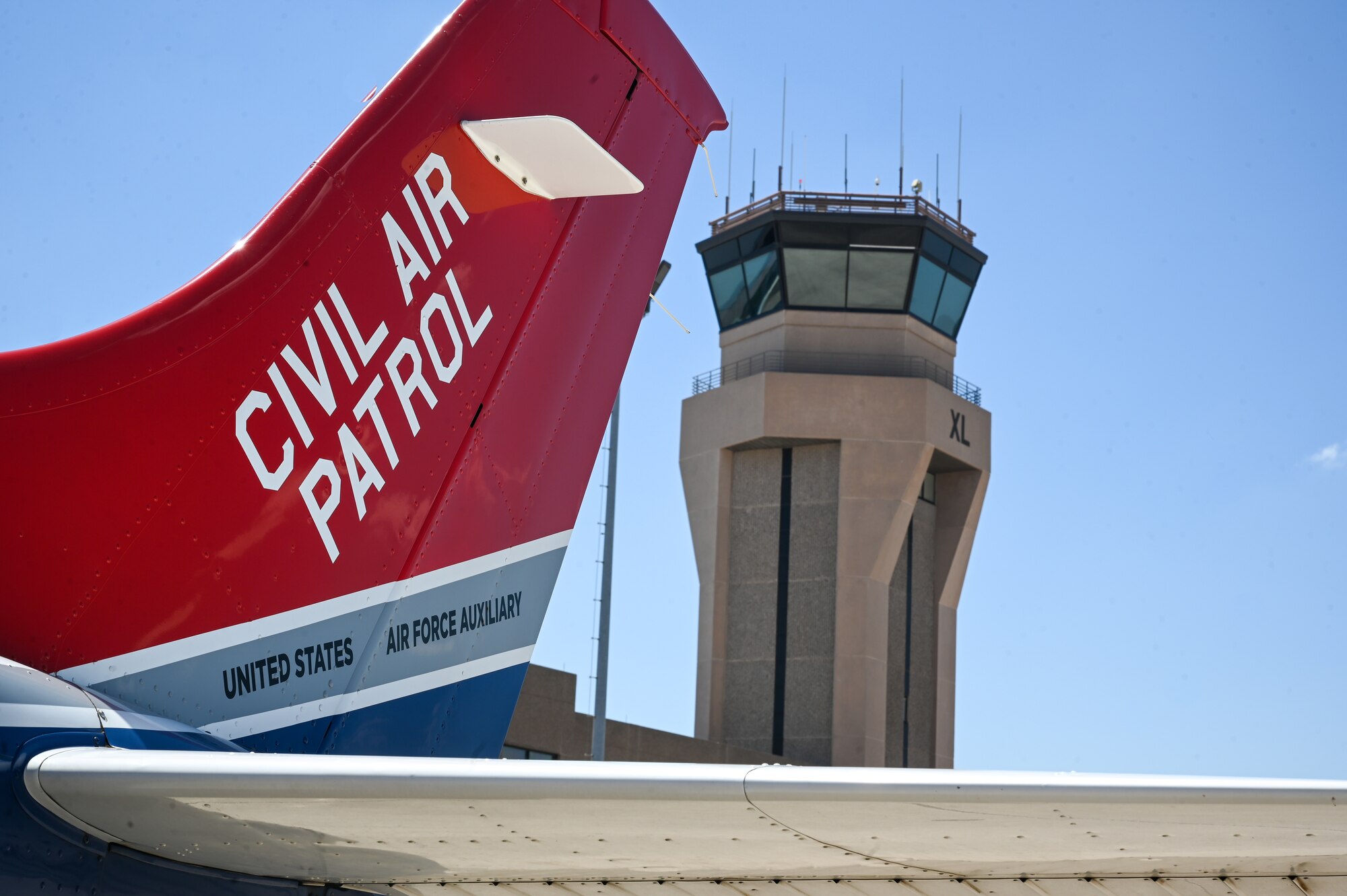 A Civil Air Patrol C-182 aircraft sits on the flightline with the air traffic control tower in the background at Laughlin Air Force Base, Texas, June 28, 2023.