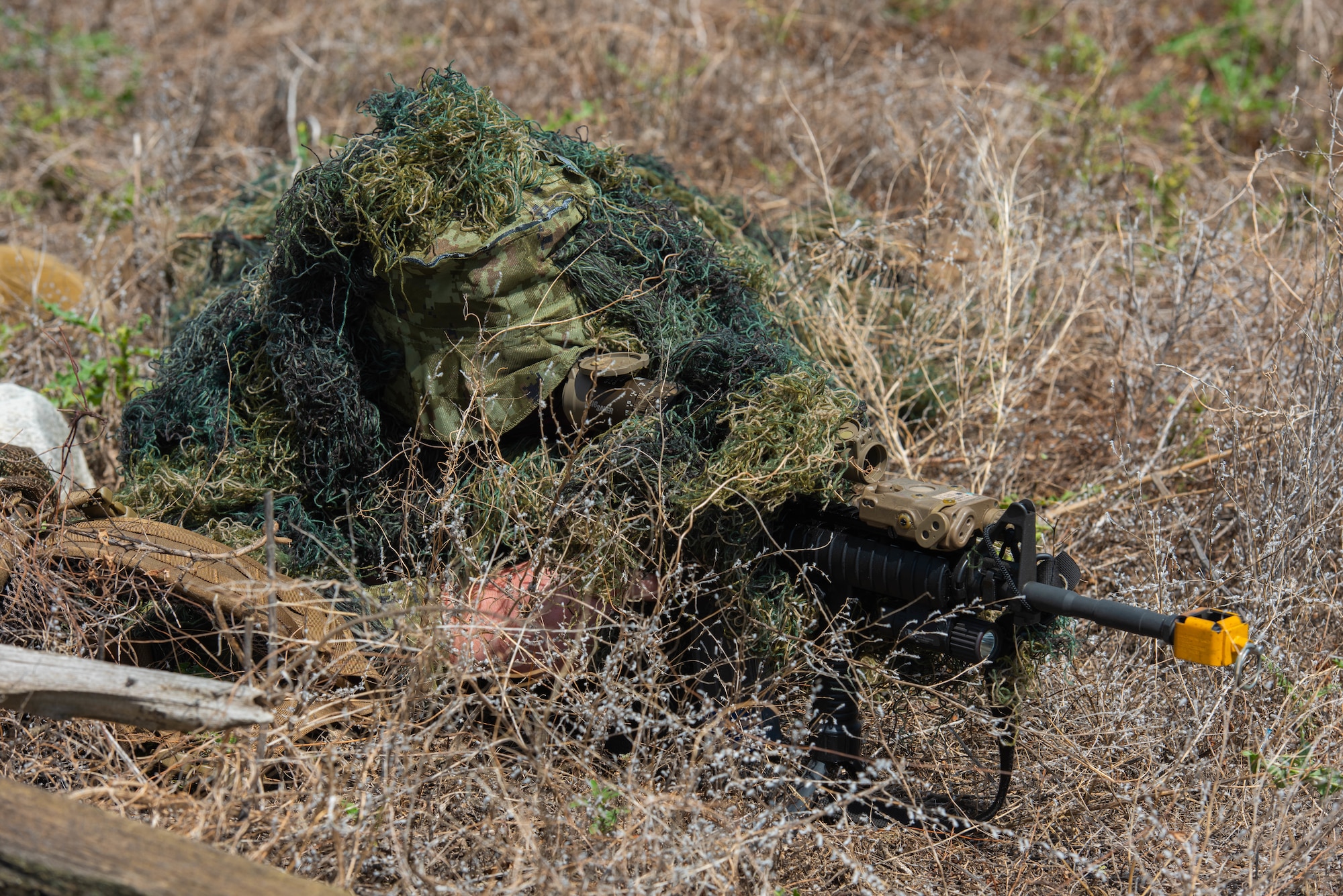 U.S. Air Force Master Sgt. Christopher Ashcraft, 219th Security Forces Squadron defender, fires blanks from an M-4 assault rifle in Mountrail County, North Dakota, July 7, 2023. Ashcraft simulated an ambush on a convoy from a hidden sniper position during a recapture and recovery exercise in order to measure security forces readiness. (U.S. Air Force photo by Airman 1st Class Kyle Wilson)