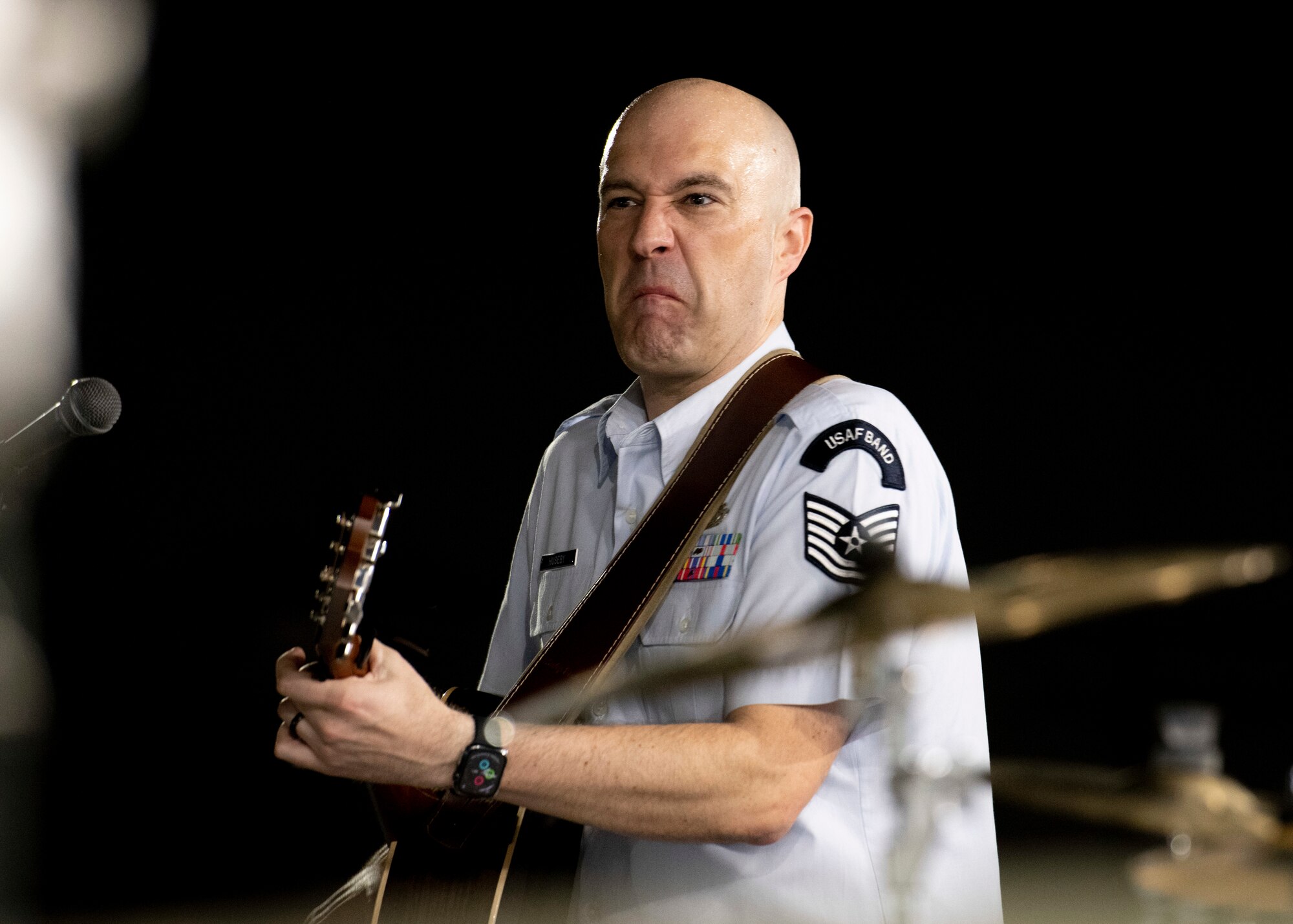 A military guitarist shows a face of concentration while playing rock music