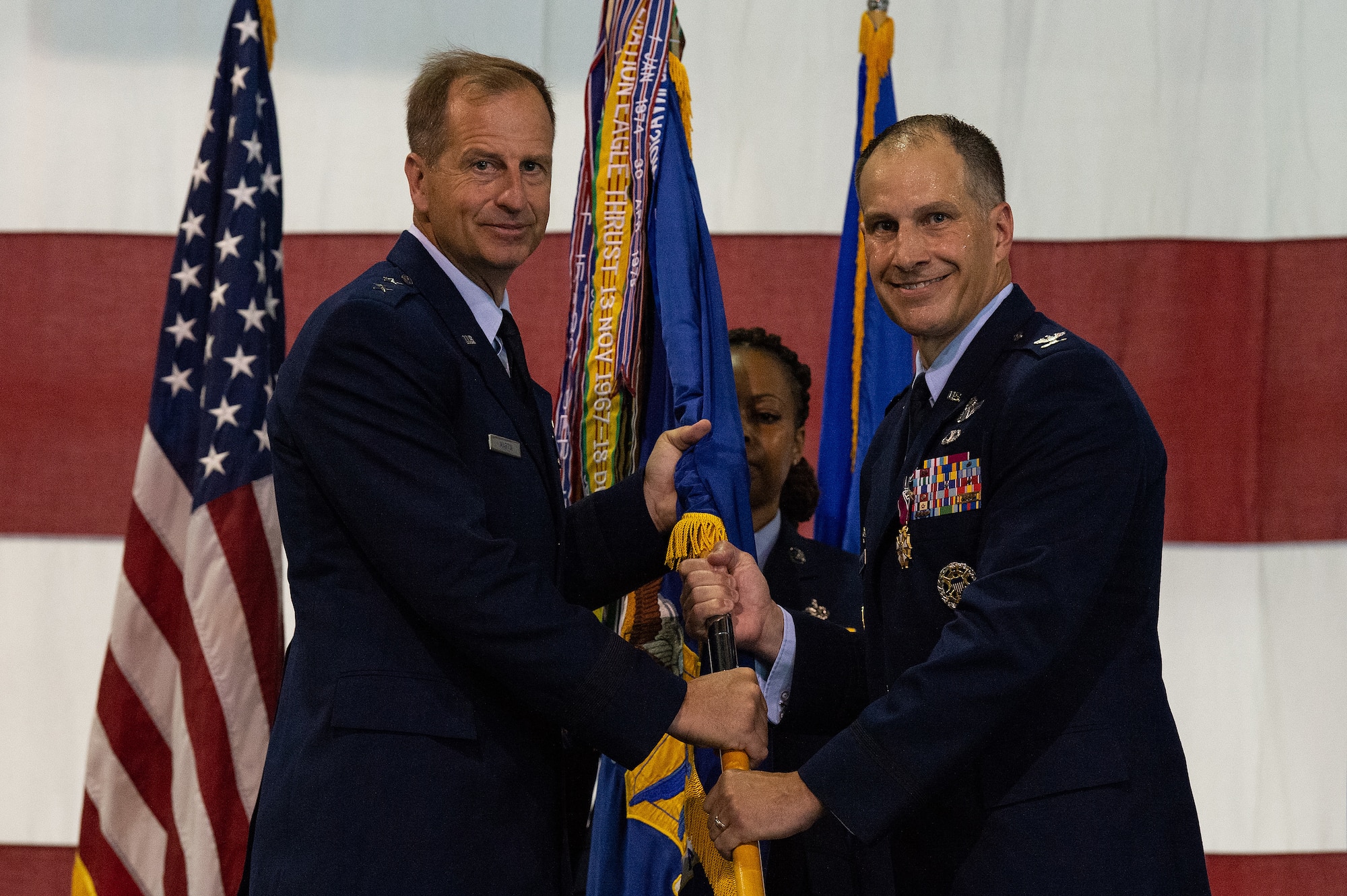 Col. Matthew S. Husemann, right, outgoing 436th Airlift Wing commander, hands the wing’s guidon to Maj. Gen. Corey J. Martin, left, 18th Air Force commander, as he relinquishes command during a Change of Command ceremony at Dover Air Force Base, Delaware, July 7, 2023. Husemann relinquished command to Col. William C. McDonald, who became the wing’s 37th commander. (U.S. Air Force photo by Roland Balik)