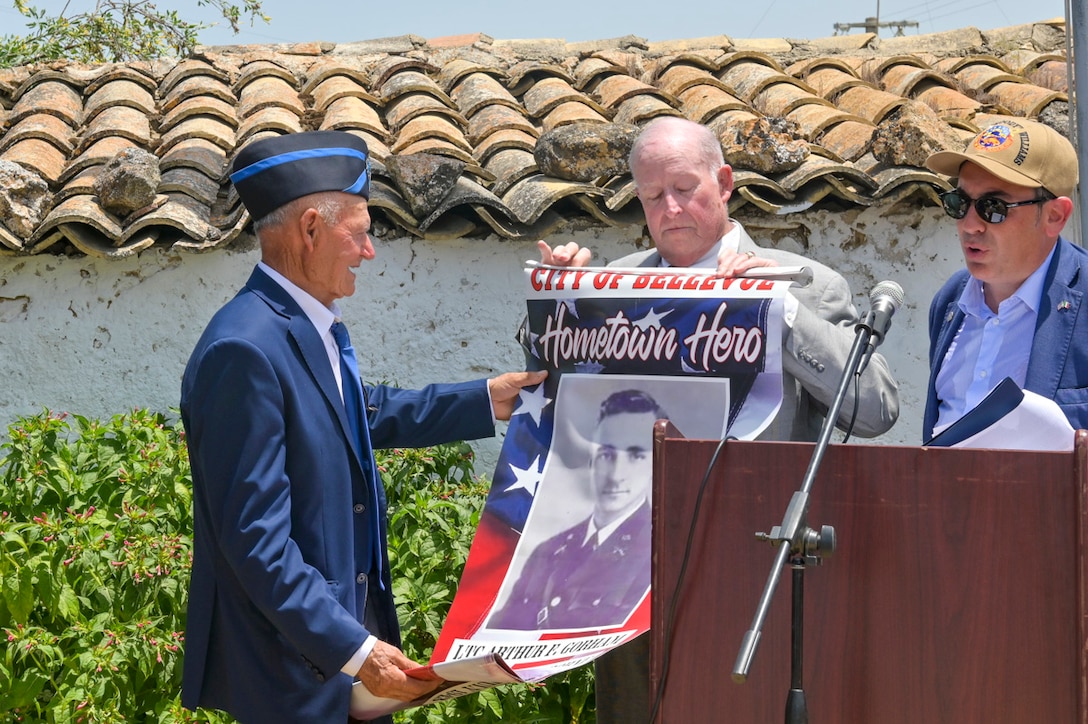 A veteran is presented a poster with a picture of his father during a ceremony.