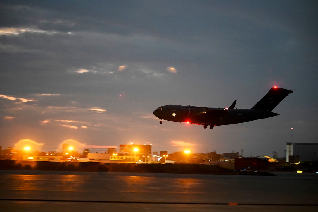 A large aircraft lands at an airport at night.
