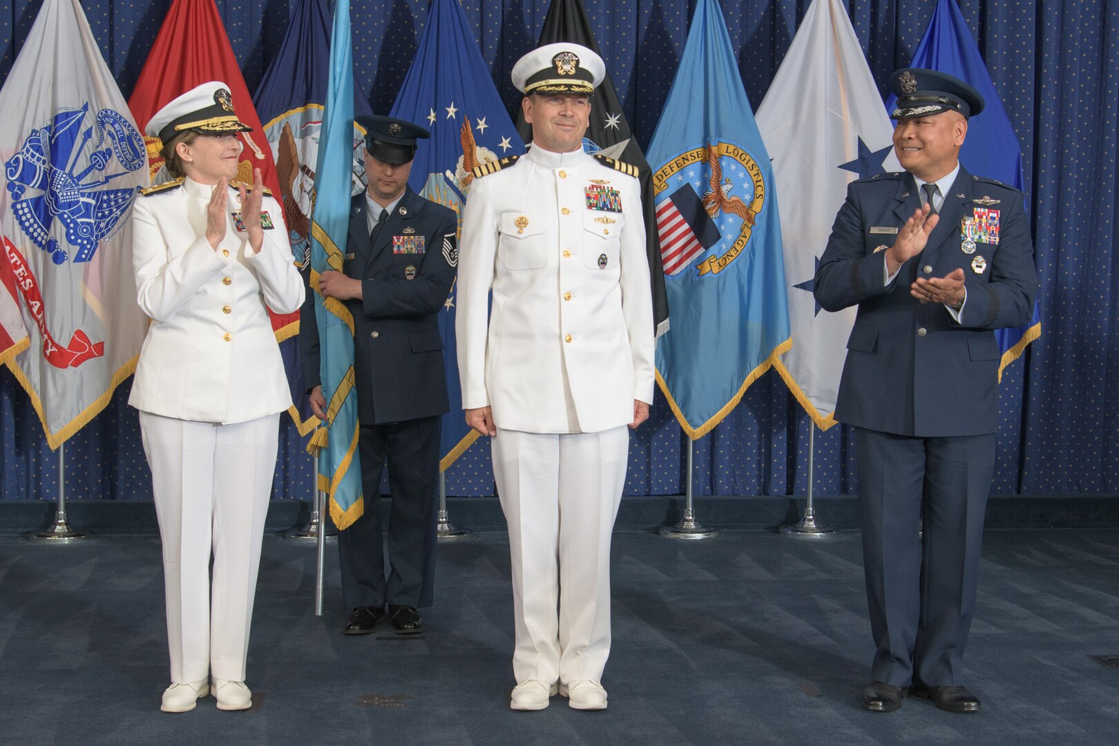 three military general officers stand on a stage
