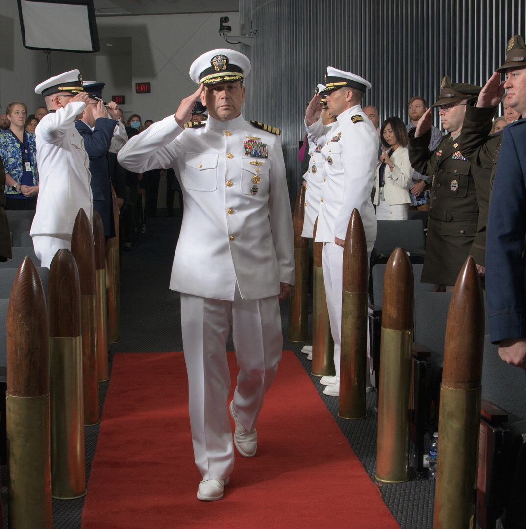 a military general officer walks down an aisle while saluting