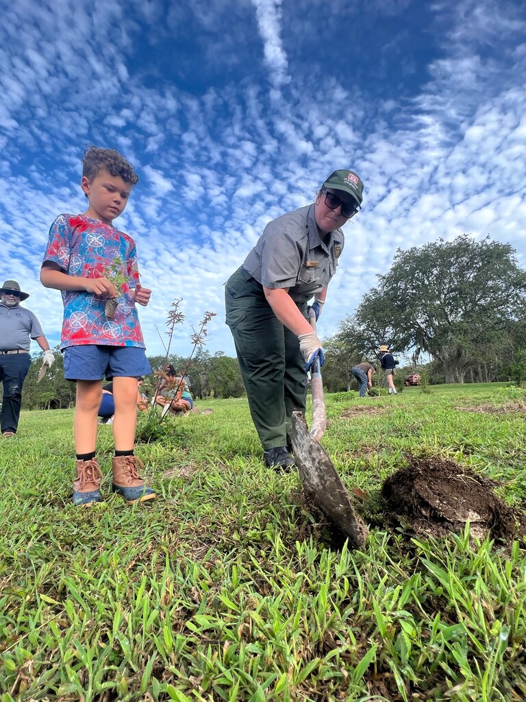 Jacksonville District Park Ranger, Megan Parsons (right) helps a volunteer to dig and plant a tree.  Volunteers will plant nearly 9,000 native pollinator wildflowers and grasses at the W.P. Franklin Recreation Area during Pollinator Week on June 24, in the second phase of plantings to reforest an 8.5 acre open field as part of the Engineering with Nature Program. (USACE photo by Mark Rankin)