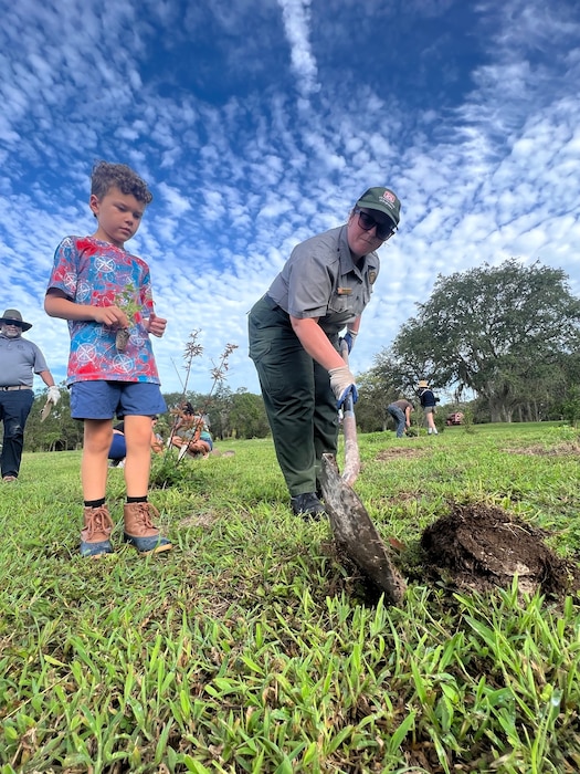 Jacksonville District Park Ranger, Megan Parsons (right) helps a volunteer to dig and plant a tree.  Volunteers will plant nearly 9,000 native pollinator wildflowers and grasses at the W.P. Franklin Recreation Area during Pollinator Week on June 24, in the second phase of plantings to reforest an 8.5 acre open field as part of the Engineering with Nature Program. (USACE photo by Mark Rankin)