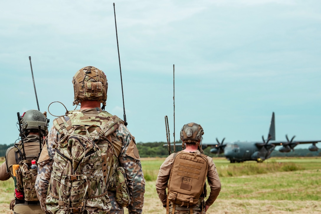 Soldiers watch a plane land.