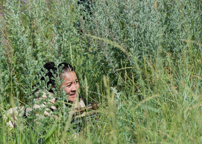 Tech. Sgt. Shareen Mendiola, 219th Security Forces Squadron defender, hides in vegetation in Mountrail County, North Dakota, July 7, 2023. Mendiola acted as a member of an opposing force during a security forces readiness exercise. (U.S. Air Force photo by Airman 1st Class Kyle Wilson)
