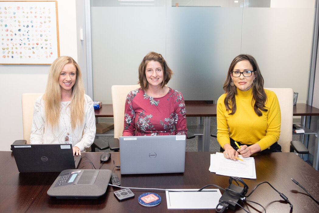 Three women sitting at a desk.