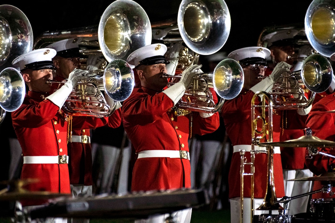 Marines play brass instruments during a nighttime parade.