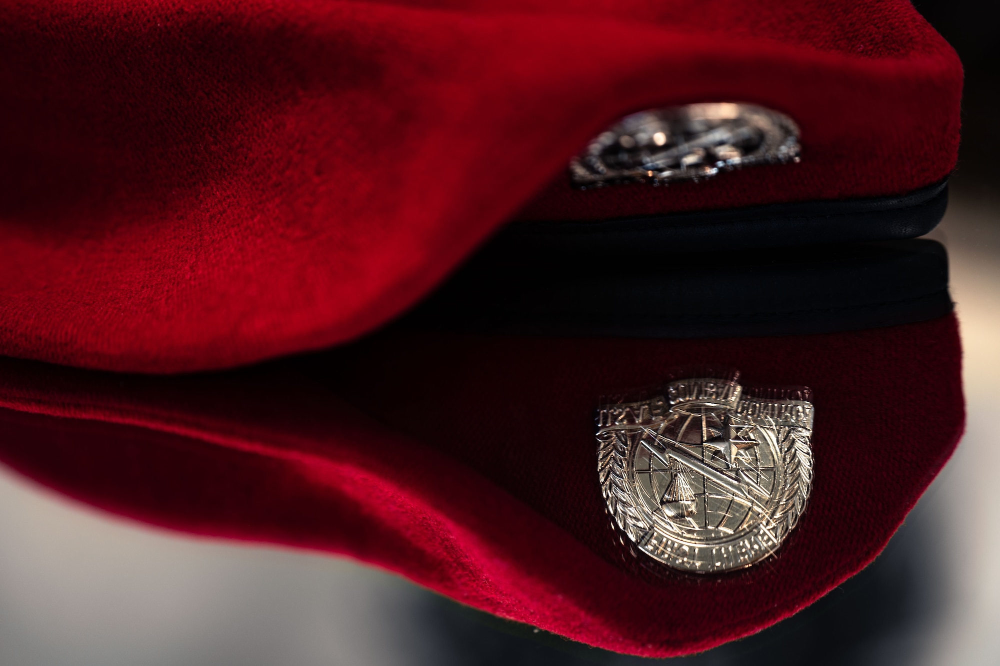 scarlet beret reflects in mirror with Combat Control pin brightly illuminated