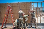 Airmen from the 103rd Airlift Wing raise plywood panels to the exterior wall of a future single-family house meant for disabled veterans of Cherokee Nation in Tahlequah, Oklahoma, June 29, 2023.