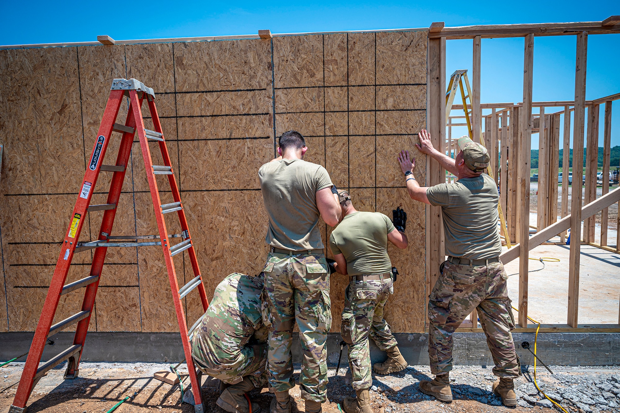 Airmen from the 103rd Airlift Wing raise plywood panels to the exterior wall of a future single-family house meant for disabled veterans of Cherokee Nation in Tahlequah, Oklahoma, June 29, 2023.