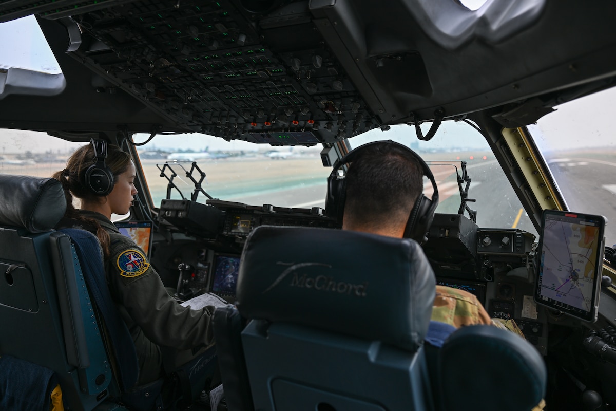 Photo of two Airman in C-17 cockpit piloting the aircraft.