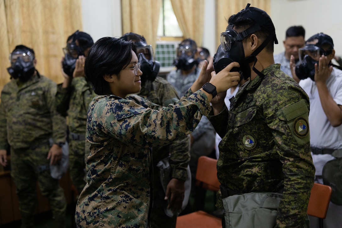 U.S. Marine Corps Pfc. Krystle Pidor, left, a chemical, biological, radiological, and nuclear (CBRN) responder with Combat Logistics Regiment 17, 1st Marine Logistics Group, helps Philippine Army Pfc. Melchor Comisario with his gas mask during Marine Aviation Support Activity (MASA) 23 at Camp Lapu Lapu, Philippines, July 10, 2023. MASA is a bilateral exercise between the Armed Forces of the Philippines and the U.S. Marine Corps, aimed at enhancing interoperability and coordination focused on aviation-related capabilities. During MASA 23, Filipino and U.S. Marines conduct different training evolutions, including live-fire, air assaults, and subject matter expert exchanges across aviation, ground, and logistics capabilities. Pidor was born in Cebu, Philippines and moved to the United States at the age of six. After 13 years, this is her first time back. (U.S. Marine Corps photo by Lance Cpl. Hannah Hollerud)