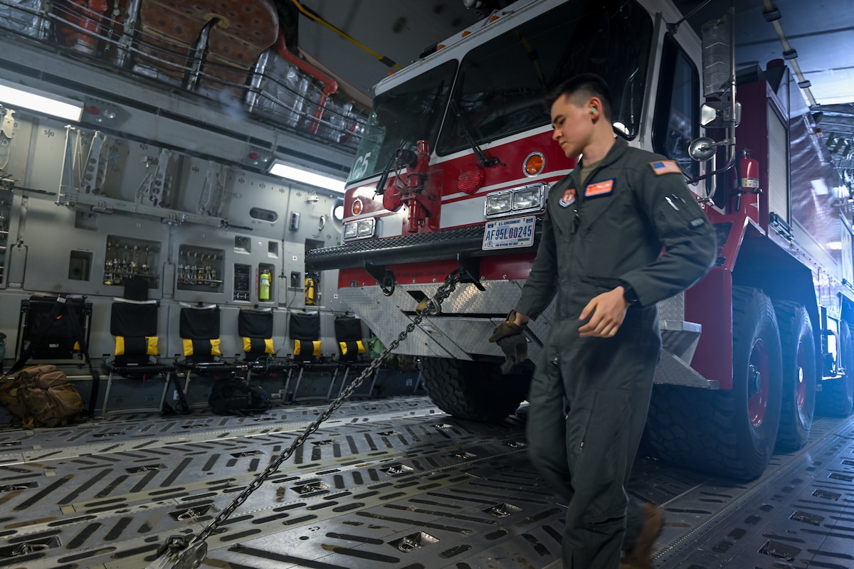 Photo of individual inside C-17 next to a firetruck.