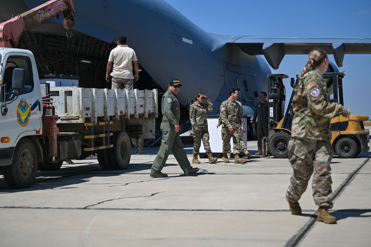 Photo of people walking around C-17 and a truck.