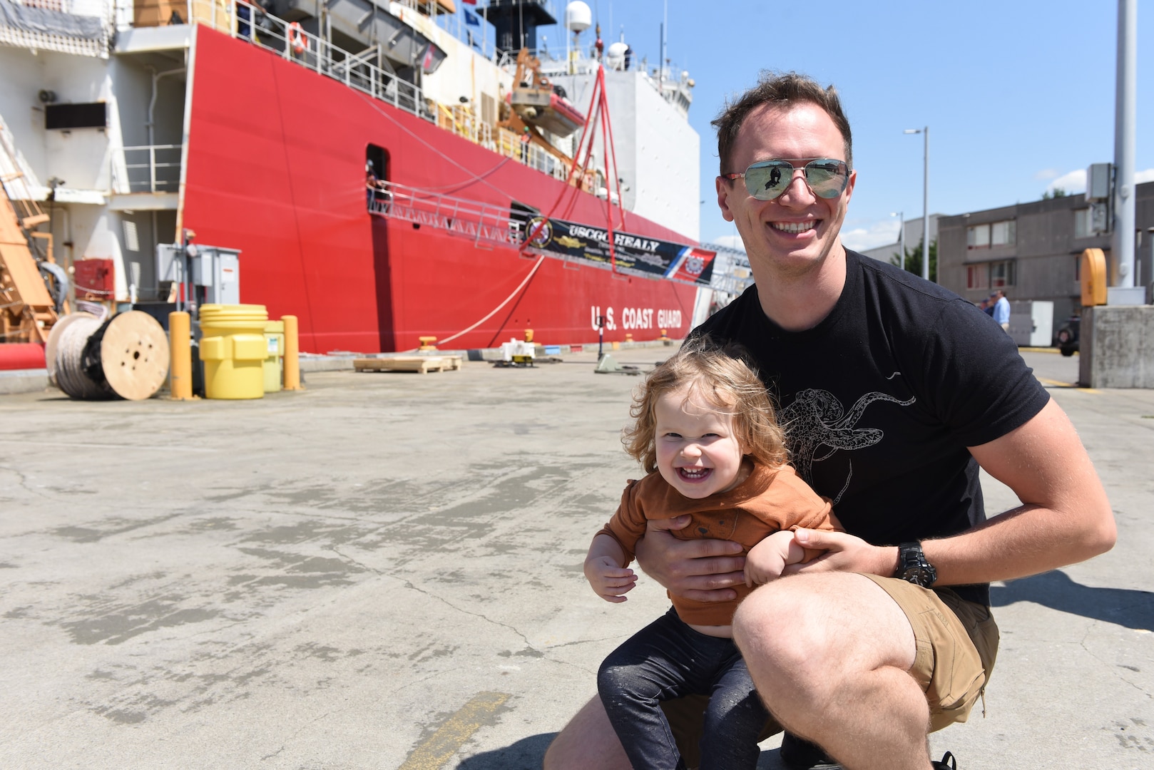 Family members of the Coast Guard Cutter Healy crew prepare to wave goodbye from the pier in Seattle, July 11, 2023. The Healy is one of two icebreakers in the Coast Guard and is the only military ship dedicated to conducting research in the Arctic. (U.S. Coast Guard photo by Petty Officer 3rd Class Annika Hirschler)