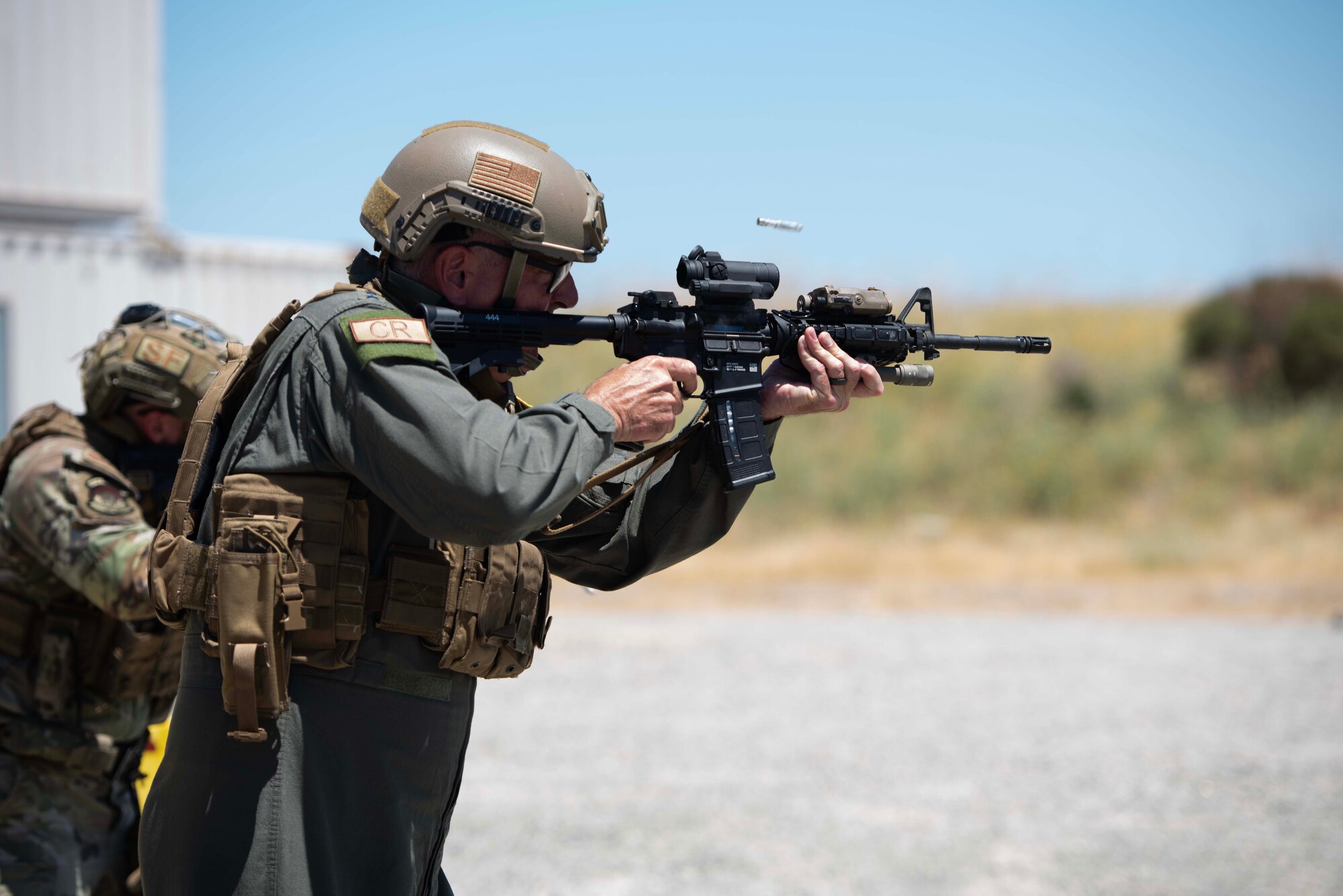 Two Airmen fire a M4 with a 5.56 simunition training round casing exiting the rifle.