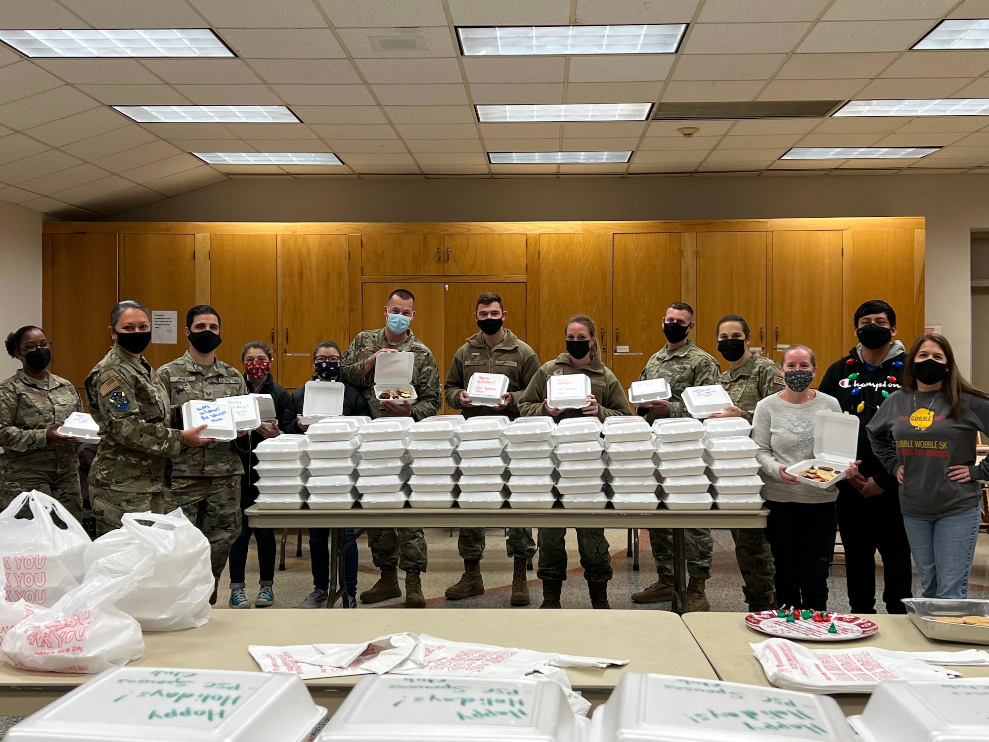 Chief Master Sgt. Sevin Balkuvvar poses for photo with fellow teammates who are building to-go boxes filled with holiday treats for servicemembers.