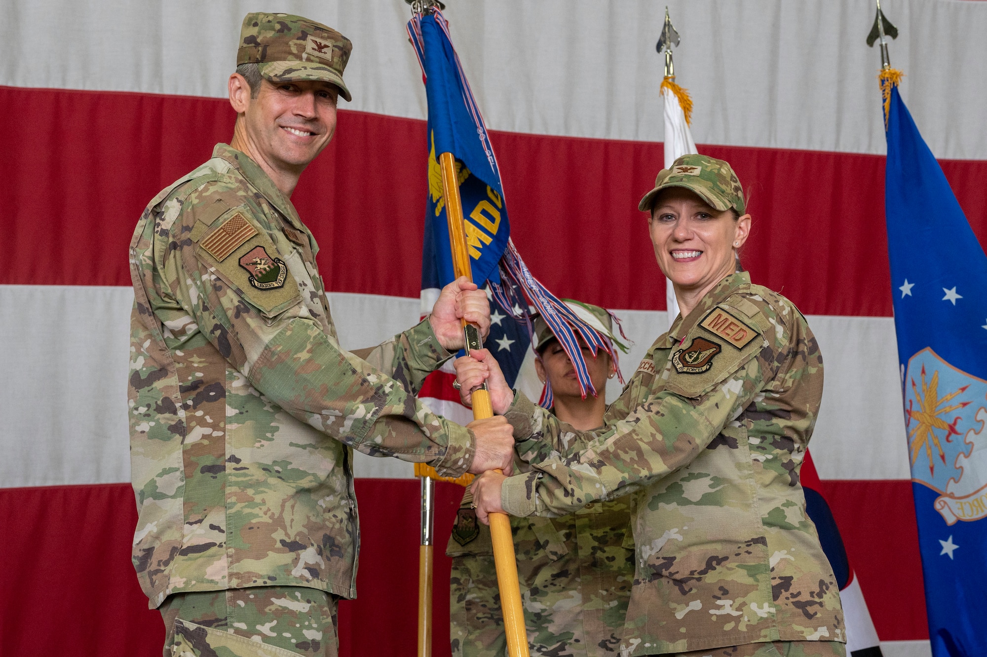 U.S. Air Force Col. William McKibban, left, 51st Fighter Wing commander, receives the guidon from Col. Jennifer Vecchione, 51st Medical Group outgoing commander, at Osan Air Base, Republic of Korea, July 12, 2023. In a change of command ceremony, the guidon symbolizes the transfer of command, the authority and responsibility associated with it.  (U.S. Air Force photo by Senior Airman Aaron Edwards)