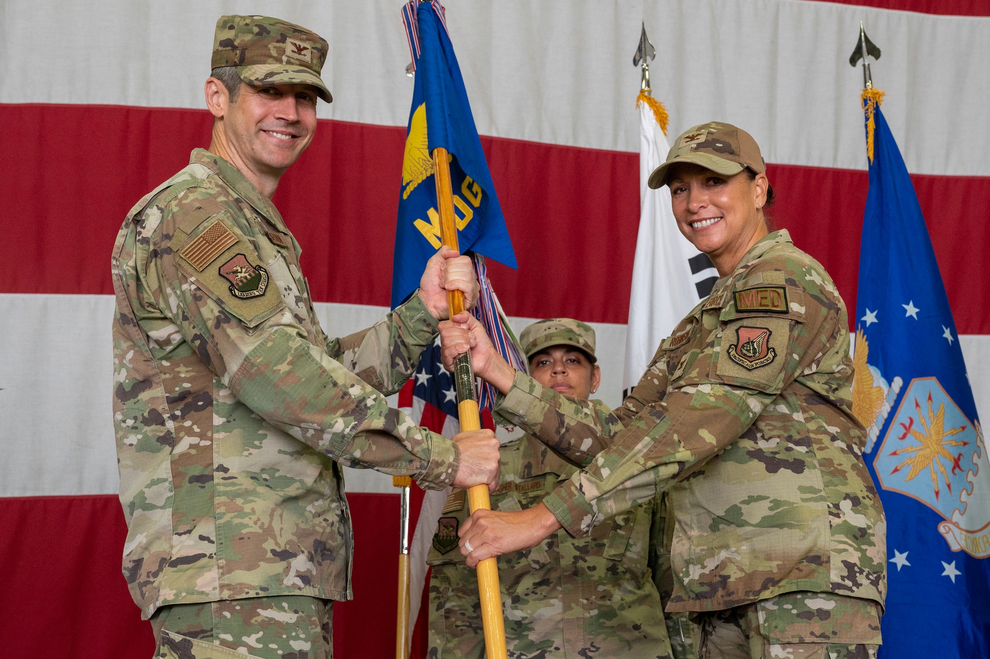 U.S. Air Force Col. William McKibban, left, 51st Fighter Wing commander, presents the guidon to Col. Mocha Robinson 51st Medical Group incoming commander, as a symbol of her taking command at Osan Air Base, Republic of Korea, July 12, 2023. Prior to taking command, Robinson served as chief, medical manpower and personnel division, office of the Air Force surgeon general, Falls Church, Virgina. (U.S. Air Force photo by Senior Airman Aaron Edwards)