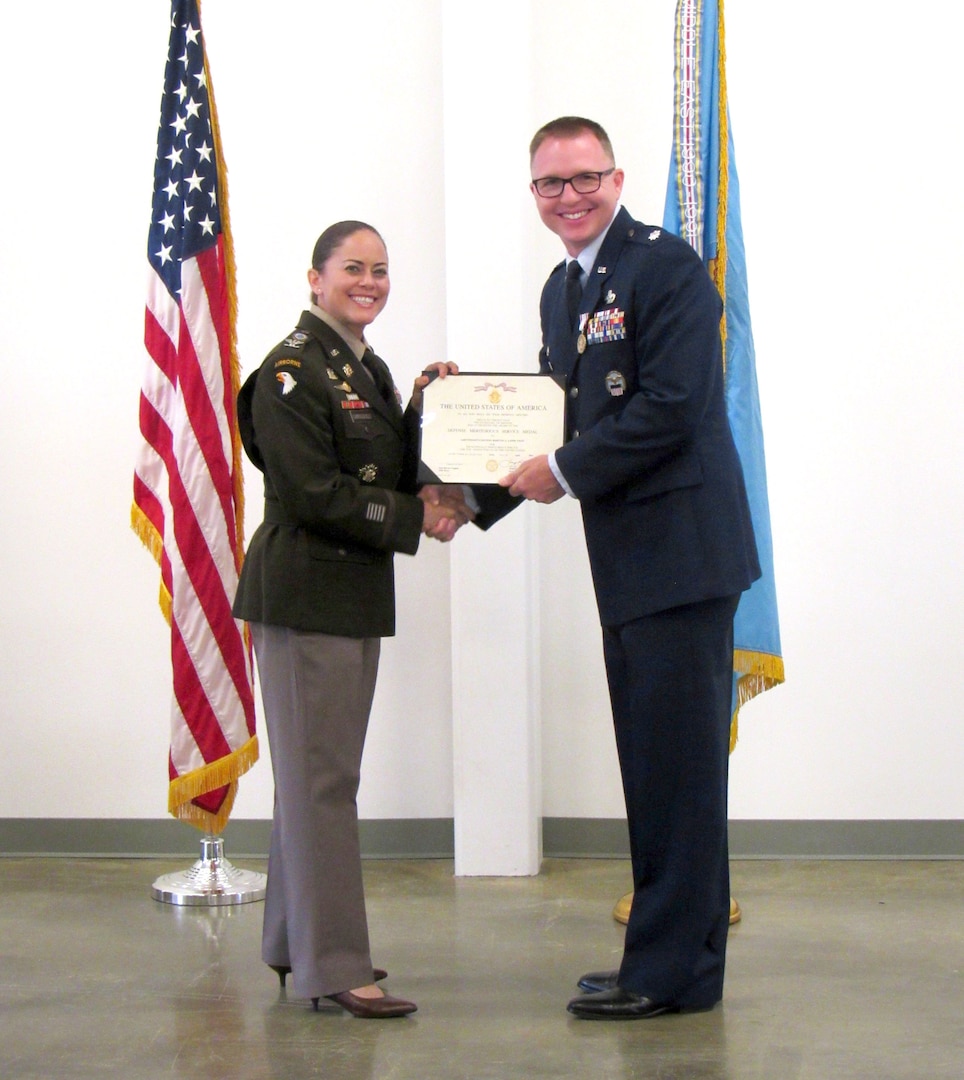 two military officers shake hands while holding a certificate