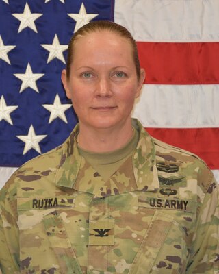 Female Soldier posed in front of U.S. flag.