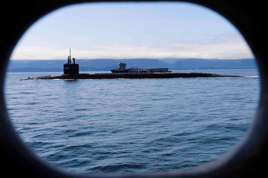 A submarine travels through a body of water next to another ship.