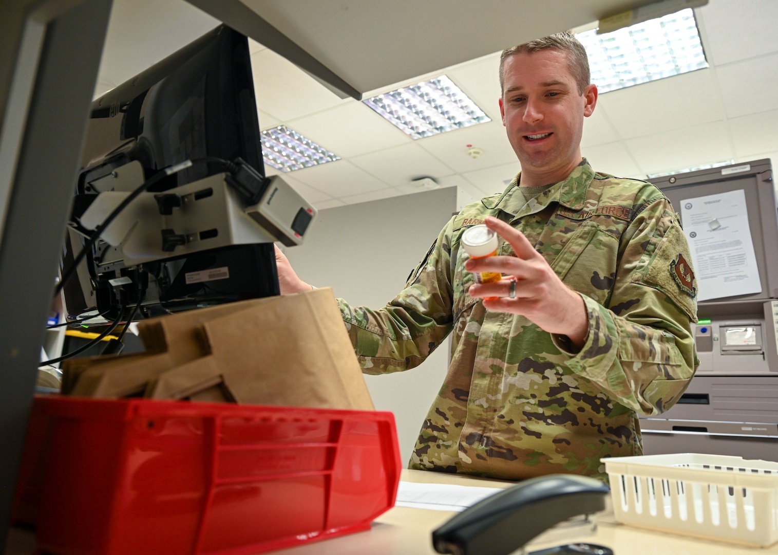 A U.S. Air Force pharmacist holds a prescription bottle in a military pharmacy.