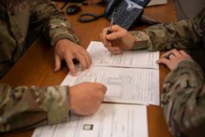 Two airmen work on filling out documents.