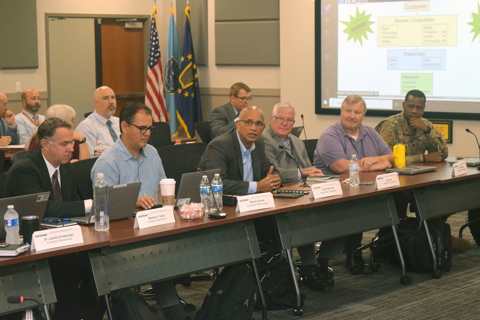 Two rows of people sitting at desks participating in discussions.